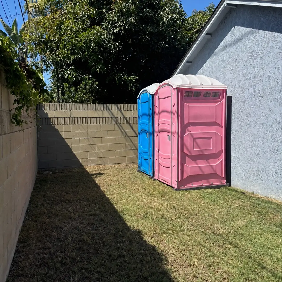 Porta potties set up in a fenced backyard for a party