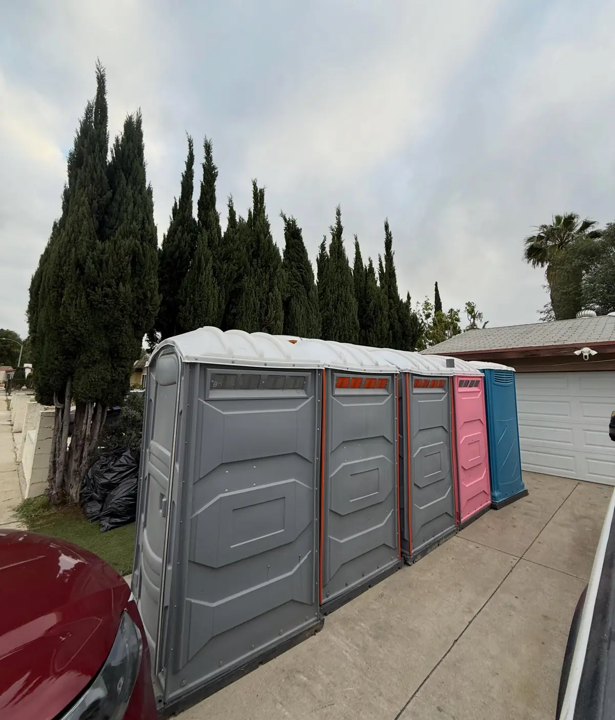 Row of standard porta potties lined up on a driveway for an event